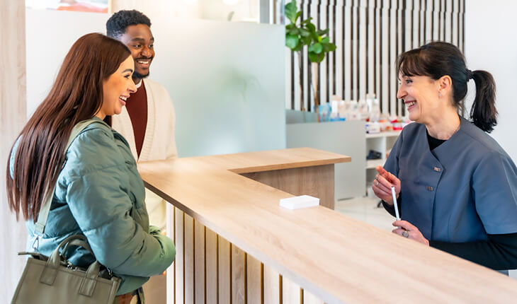 A woman converses with a man at a reception desk, both engaged in a friendly discussion.